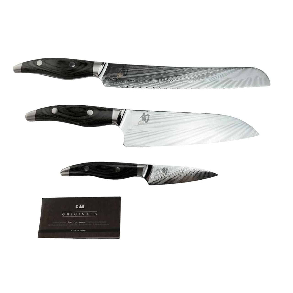 Abgebildet sind drei Messer mit Damaszenerstahlklingen und schwarzen Griffen, von oben nach unten angeordnet als Brotmesser, Kochmesser und Schälmesser. Neben den Messern befindet sich eine kleine Karte mit der Aufschrift „Kai Originals“. Diese exquisiten Stücke eignen sich perfekt als Ergänzung zu Ihrem Messerblock aus Fassholz, der die 3 Kai Shun Nagare Messer (NDC-0700-0702-0705) enthält.