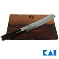 Ein gezahntes KAI Shun Premier Tim Mälzer Brotmesser mit gemusterter Damaststahlklinge und dunklem Holzgriff liegt auf einem zweifarbigen, robusten 30x18 cm Fassholzbrett-Schneidebrett. Das Brett trägt in der Mitte ein Logo und die Klinge des Messers weist wellenartige Texturen auf. Das blaue Kai-Logo befindet sich in der unteren rechten Ecke.