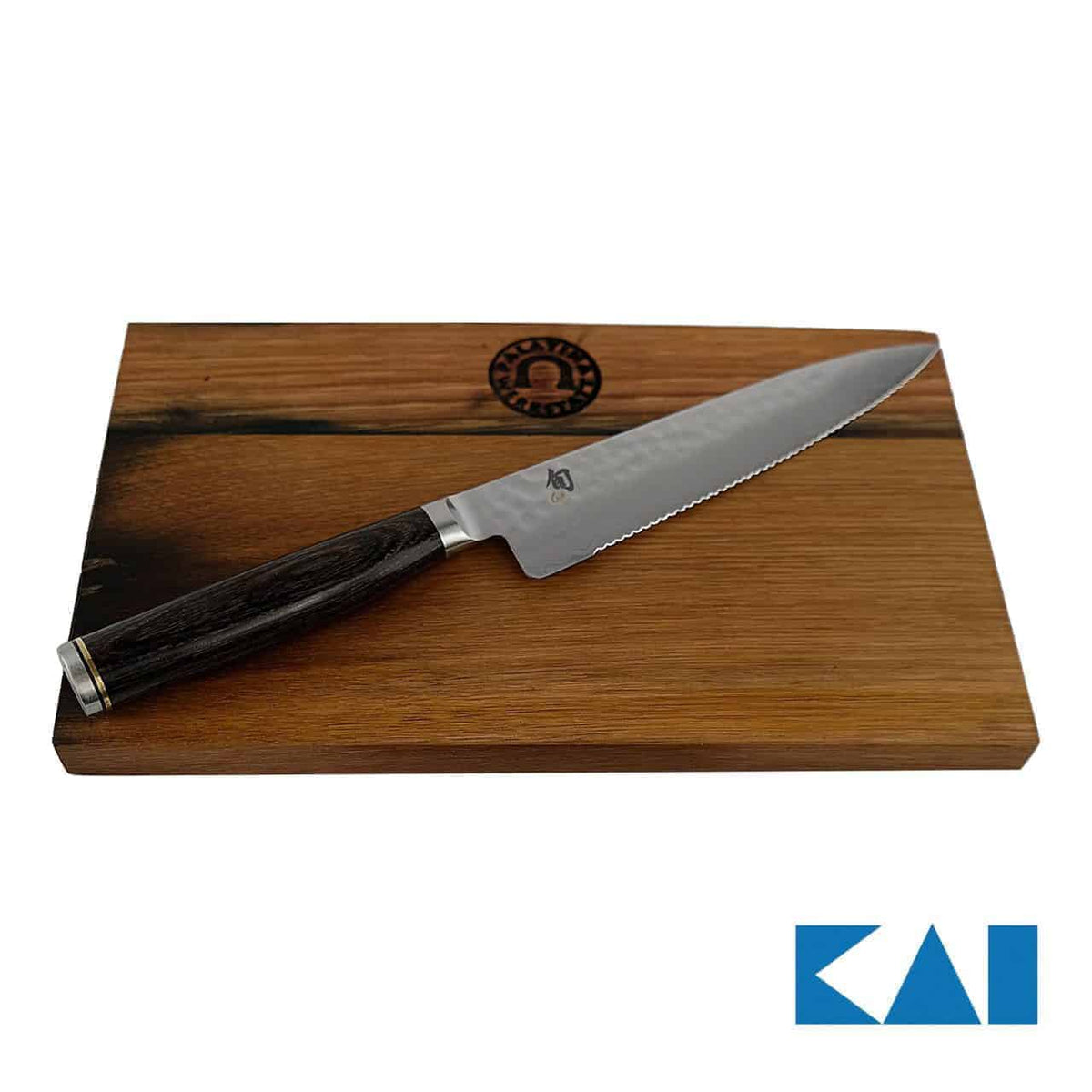 Ein KAI Shun Premier Tim Mälzer TDM-1722 Allzweckmesser, ein gezahntes Tomatenmesser mit dunklem Griff, liegt auf einem Fassholz-Schneidebrett mit den Maßen 25 x 15 cm. Das Schneidebrett ist mit einem eingravierten Logo versehen, während die markant gemusterte 16,5 cm lange Klinge einen Wellenschliff und ein kleines Logo aufweist. Das Bild zeigt außerdem das KAI Shun Premier-Logo in der unteren rechten Ecke.