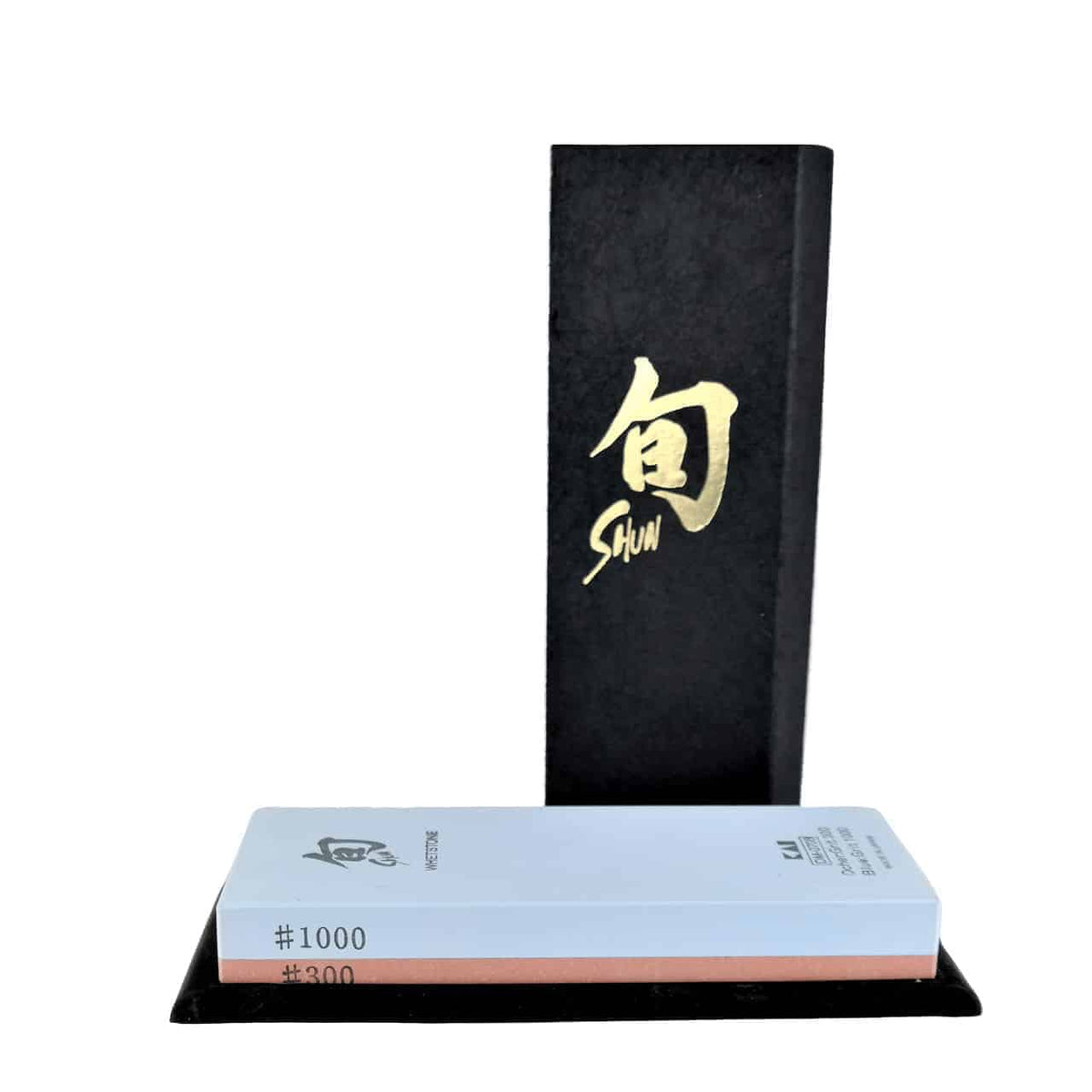 Das Kai DM-0708 Kombi-Wasserschleifstein-Set enthält einen doppelseitigen Schleifstein mit Körnungen von #300 und #1000, ergänzt durch einen eleganten schwarzen Ständer. Das elegante schwarze Gehäuse zeigt goldene japanische Kanji sowie das „Shun“-Logo in edlem Goldschriftzug, während der rechteckige Schleifstein kontrastierende blaue und rosa Seiten aufweist. Zusätzlich wird das Set mit einem Poliertuch geliefert.