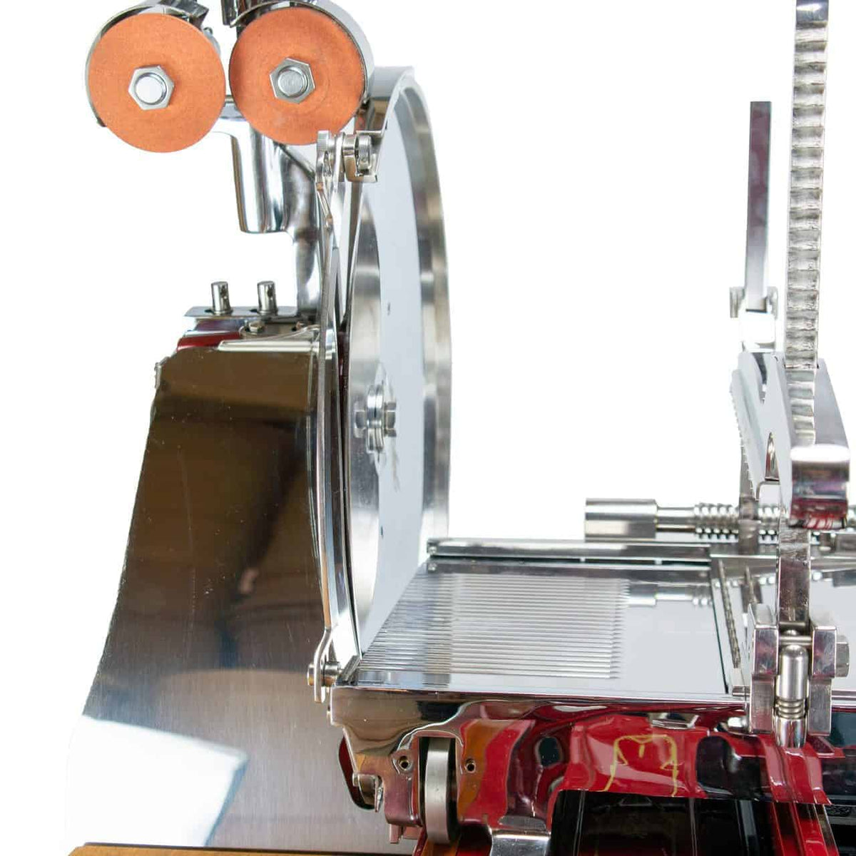 Nahaufnahme der Berkel Volano L16 nostalgischen Schwungrad-Aufschnittmaschine in Rot, mit großem Rundmesser, Lebensmittelhalter und glatten Metallkomponenten. Die Maschine verfügt über eine glänzende, reflektierende Oberfläche mit auffälligen roten Akzenten. Ein handgefertigtes Einlegebrett verstärkt ihren klassischen Charme vor dem weißen Hintergrund.