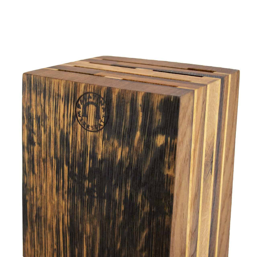 Eine Nahaufnahme eines exklusiven Messerblocks aus den Fassdauben alter Eichen-Weinfässer, der mehrere Schlitze zum Halten von Messern aufweist. Das Holz hat eine reiche, dunkle und helle Maserung, die an Eichen-Weinfässer erinnert, und oben ist ein kreisförmiges Logo mit einem Pferdekopf eingraviert.