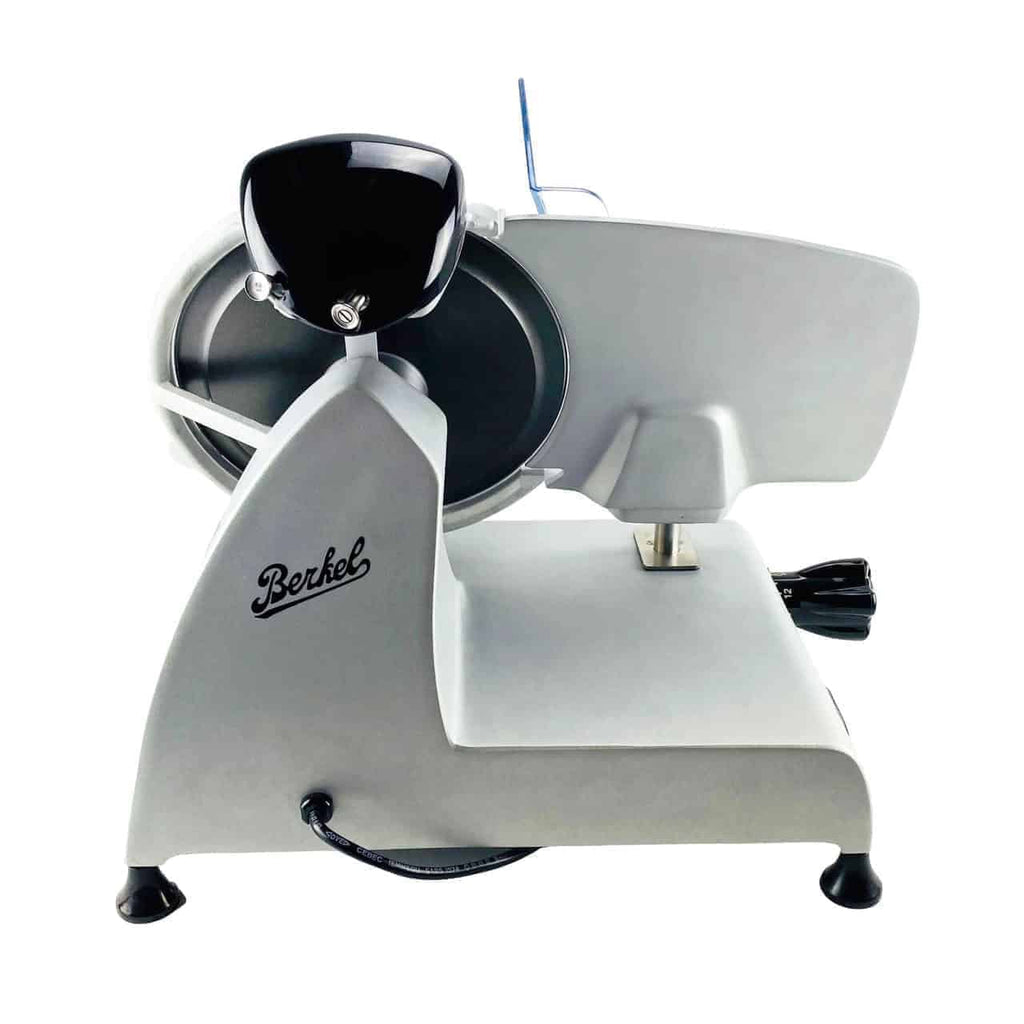 Eine Berkel Red Line 250 Grau Teflon Original Profi-Aufschnittmaschine mit silber-weißem Gehäuse, schwarzem Griff und montiertem Drehmesser. Dieser elektrische Fleischschneider hat einen Messerdurchmesser von 25 cm und zeichnet sich durch ein schlankes Design aus, das auf einer flachen Oberfläche steht. Ein Netzkabel verläuft von der Rückseite des Schneiders und er verfügt über ein Einlegebrett aus Fassholz.