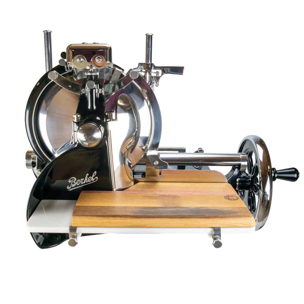 Die Berkel Volano P15 schwarz, manuelle Aufschnittmaschine mit Schwungrad+Aufschnittbrett ist eine Fleischschneidemaschine im Vintage-Stil mit einem glänzenden Metallrahmen und einem hölzernen Schneidebrett. Der schwarze Sockel hat einen Griff auf der rechten Seite und trägt deutlich sichtbar das Berkel-Markenlogo auf der Seite. Darüber hinaus ist sie mit einem eleganten Schwungrad für einen reibungslosen Betrieb ausgestattet.