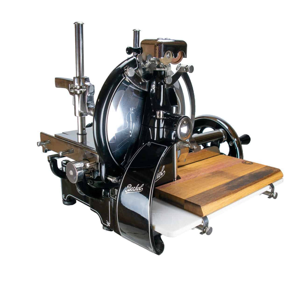 Die Berkel Volano P15 schwarz, manuelle Aufschnittmaschine mit Schwungrad+ Aufschnittbrett, ist ein antiker Fleischschneider in Schwarz und Silber mit einem hölzernen Schneidebrettaufsatz. Diese Maschine verfügt über ein großes Rundmesser und verschiedene Metallkomponenten zur Einstellung und Bedienung, was ihr einen Vintage-Industrie-Look verleiht, der an klassische Schwungrad-Designs manueller Aufschnittmaschinen erinnert.