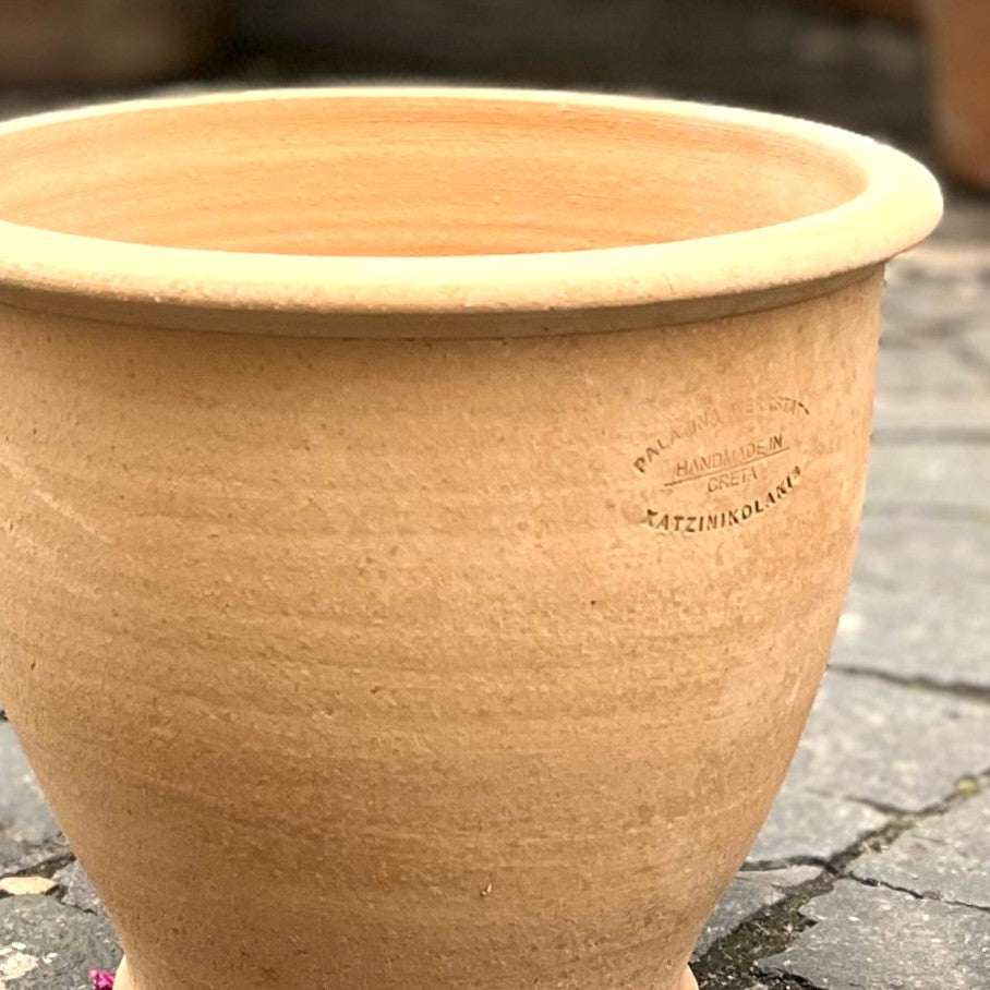 Ein großer, unglasierter Terrakotta Pflanztopf "Rubus" 30 cm - Handgemacht & Frostfest mit einem glatten, abgerundeten Rand steht auf grauen Steinfliesen. Eine gestempelte Marke an der Seite zeigt an, dass er handgefertigt ist.