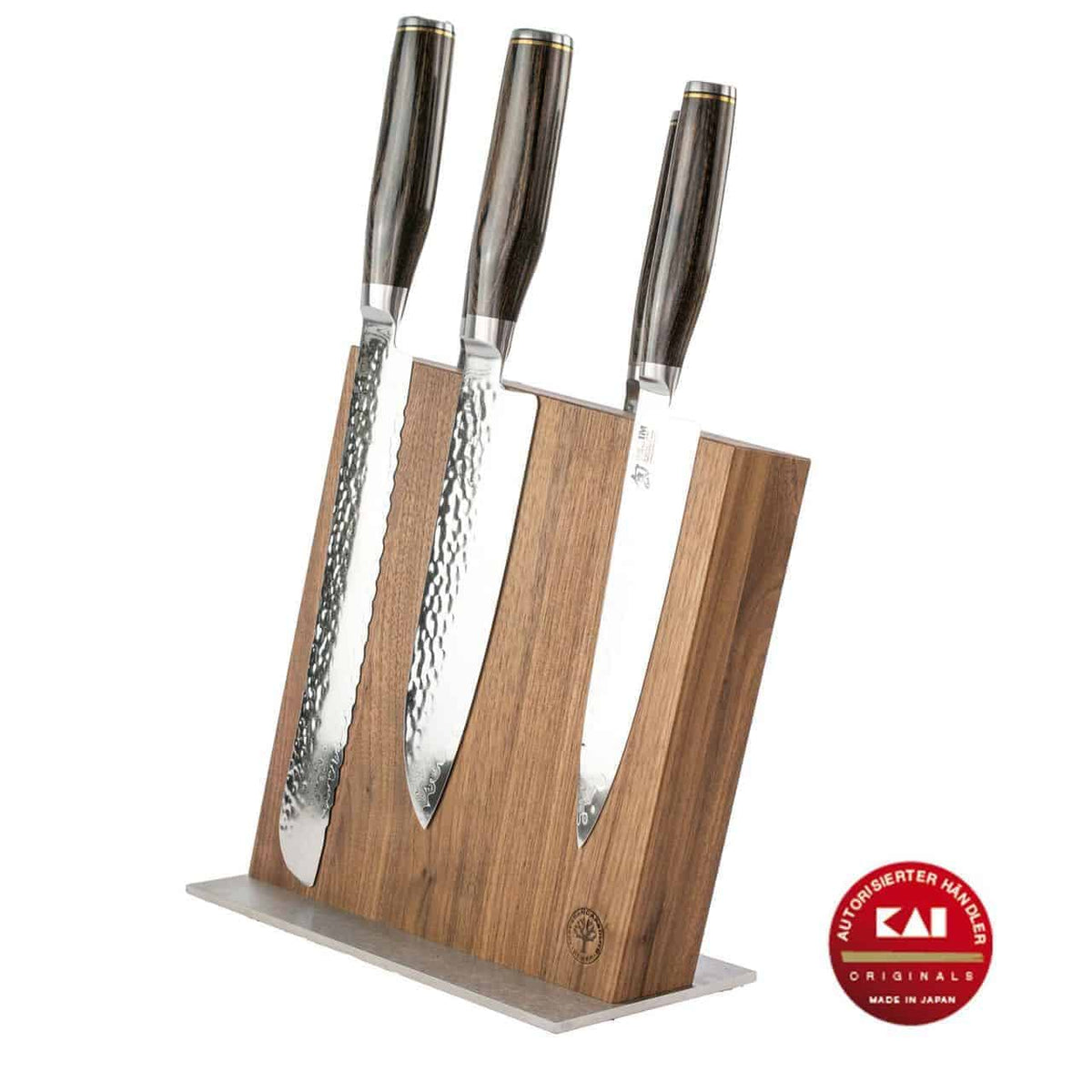 Das exklusive Messerblock-Set - KAI Shun Tim Mälzer Damastmesser mit hochwertigem Magnet-Messerblock aus Walnuss von Böker präsentiert stolz vier Kochmesser aus rostfreiem Stahl mit dunklen Griffen auf einem luxuriösen magnetischen Messerhalter aus Holz aus edlem Walnussholz. Die Klingen haben ein atemberaubendes gehämmertes Finish, das an Damastmesser erinnert. Ein rotes rundes Siegel unten rechts lautet „Kai High Performance Knives, Made in Japan“.