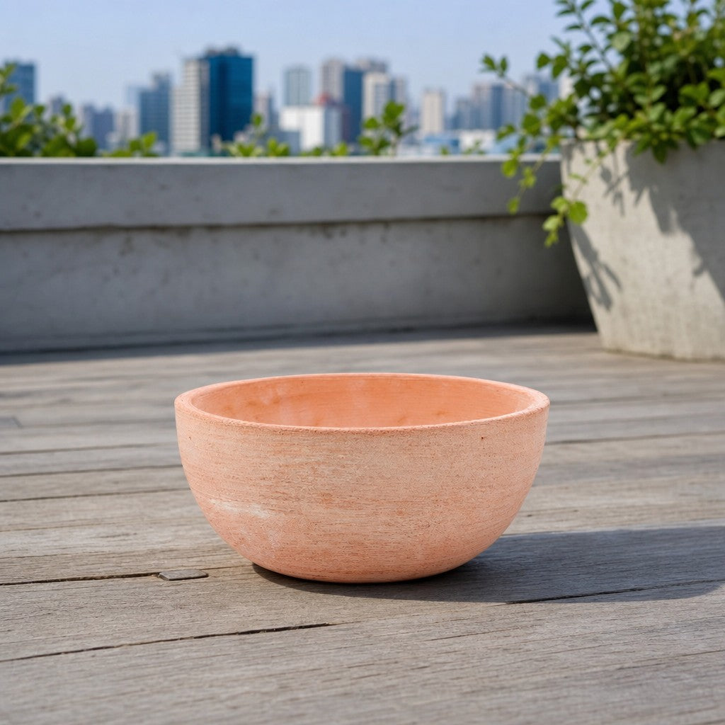 Die moderne Pflanzschale mit einem Durchmesser von 29–50 cm steht auf einer hölzernen Dachterrasse; im Hintergrund sind eine Stadt-Skyline und eine Zimmerpflanze unscharf zu erkennen.