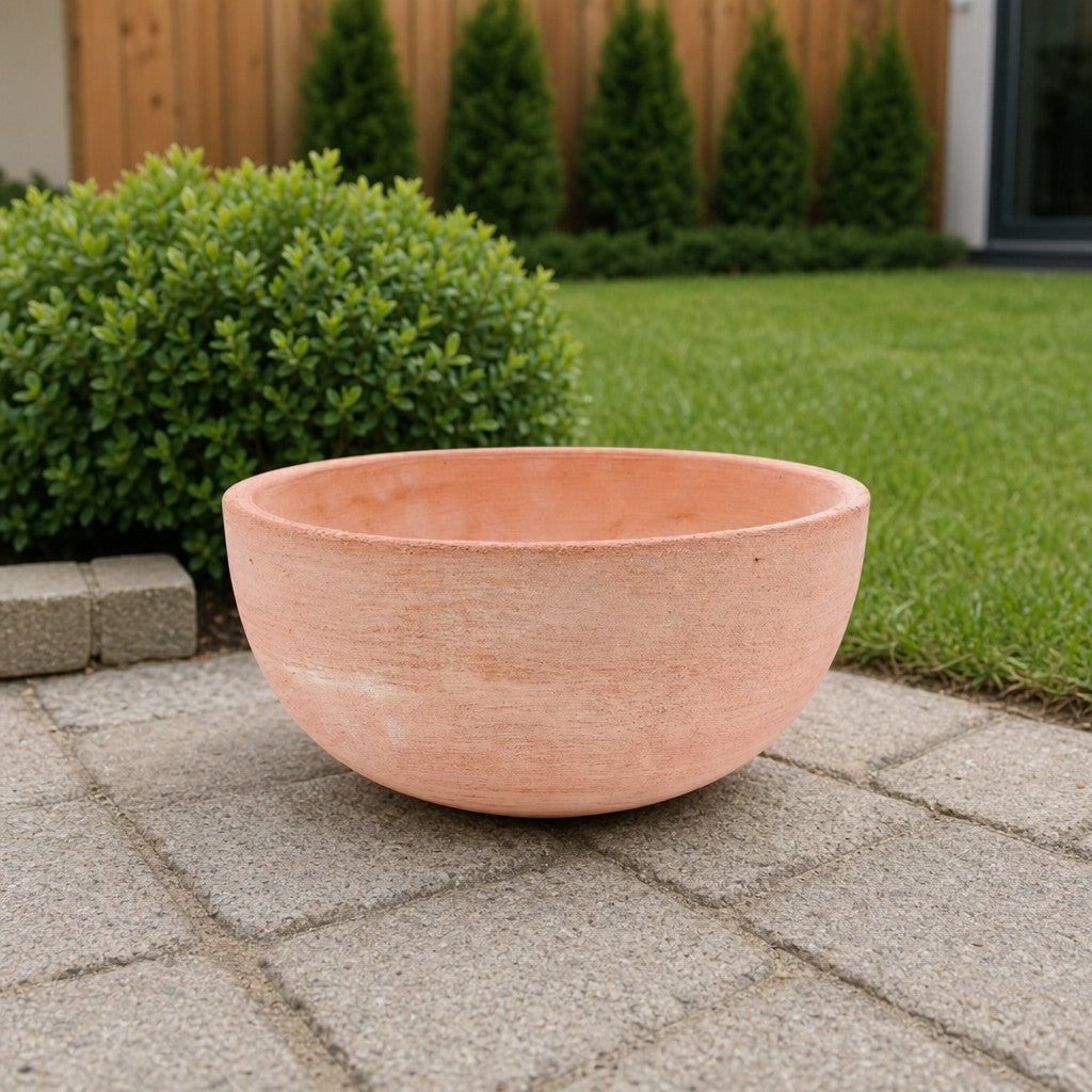 Eine moderne Pflanzschale mit einem Durchmesser von 29–50 cm steht leer auf einer Steinterrasse, im Hintergrund grüner Rasen, Sträucher und ein Holzzaun.