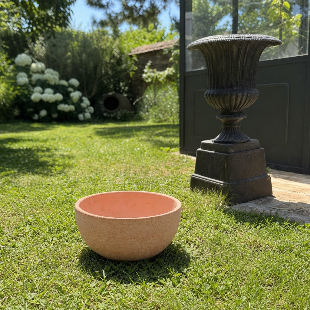 Die moderne Pflanzschale mit einem Durchmesser von 29–50 cm steht auf grünem Rasen neben einer großen schwarzen Deko-Urne im sonnigen Garten, umgeben von Sträuchern, Bäumen und einem Gewächshaus im Hintergrund.
