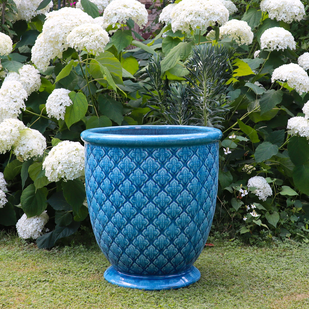Der Türkis glasierte Blumentopf "Azur Provence" (Höhe 30,5 bis 54 cm) steht auf einem grasbewachsenen Rasen, umgeben von üppig grünem Laub und blühenden weißen Hortensien.