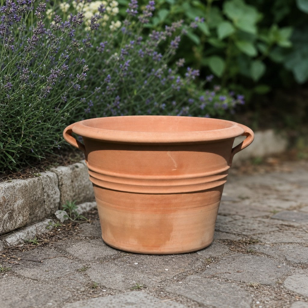 Der Terrakotta-Pflanzkübel „Sorbus“ mit Henkeln (Durchmesser 40–60 cm) steht auf einem Steinweg inmitten von blühendem Lavendel und üppigem Grün im Garten.