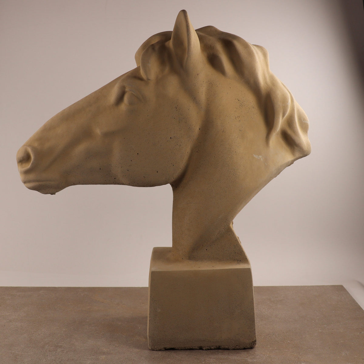 Die handgefertigte Steinfigur "Pferd groß" in Beige steht auf rechteckigem Sockel vor hellem Hintergrund - der Pferdekopf zeigt nach links und beeindruckt mit kunstvoll gearbeiteter Mähne und markanter Kopfform.