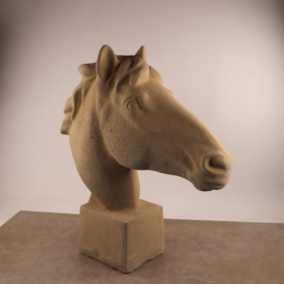 Die handgefertigte Steinfigur "Pferd groß" zeigt einen detailreichen Pferdekopf mit Mähne, Ohren und ausdrucksstarken Augen auf quadratischem Sockel - eine eindrucksvolle Dekoration für den Garten vor hellem Hintergrund.