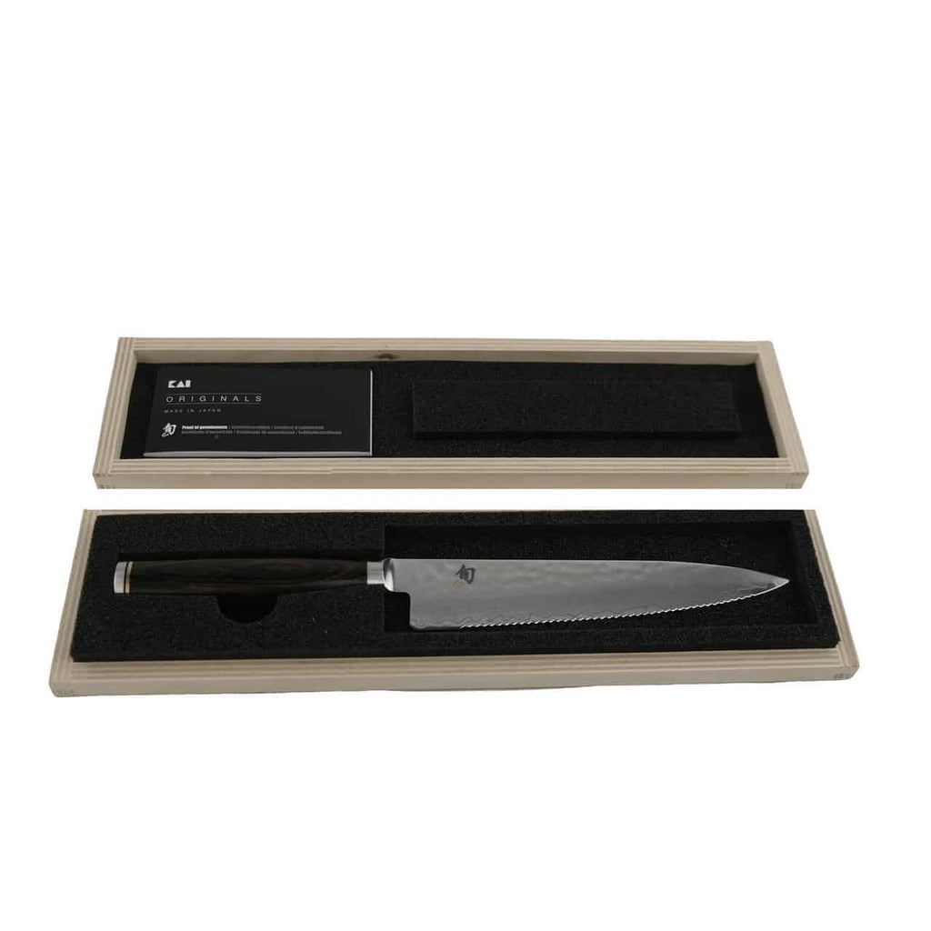 Das KAI Shun Premier Tim Mälzer TDM-1722 Allzweckmesser, ein 16,5 cm langes Tomatenmesser mit Wellenschliff-Klinge, wird in einer offenen Holzbox mit schwarzer Schaumstoffeinlage präsentiert. Das Messer mit dunklem Griff liegt ordentlich in der Schaumstoffeinlage neben einer Informationskarte.