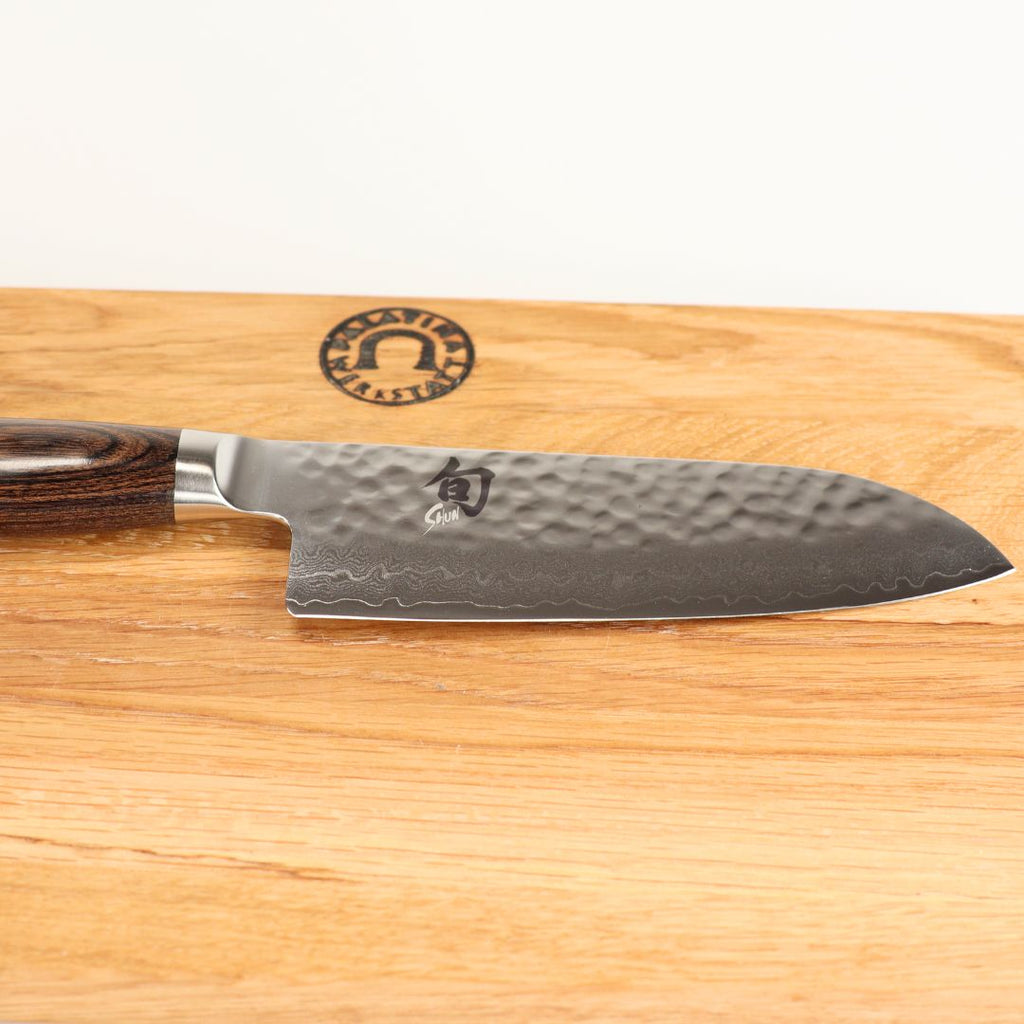 Das Kai Shun Premier Tim Mälzer TDM-1727 kleines Santoku (14 cm Klinge) liegt auf dem 30x20 cm Schneidebrett und verkörpert die Präzision eines japanischen Küchenmessers.