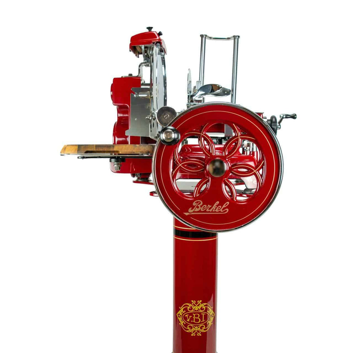 Eine Berkel Volano Tribute Rot Aufschnittmaschine, die Vintage-Elemente mit kunstvollen Verzierungen präsentiert, verfügt über ein großes dekoratives Blumenschwungrad und eine Plattform für das Fleisch. Das Wort „Berkel“ ist deutlich an der Seite dieser Maschine zu sehen. Sie ist elegant auf einem passenden roten Ständer mit goldenen Akzenten montiert, zusammen mit einem Aufschnittbrett aus Fassholz.