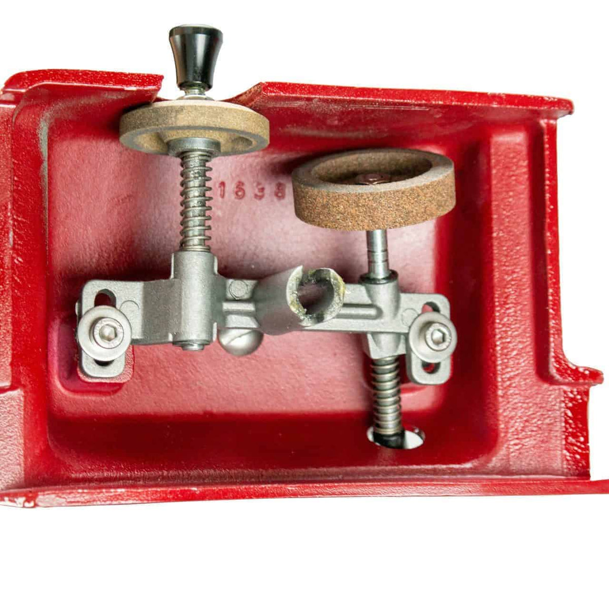 Nahaufnahme eines alten, handgekurbelten Schleifradwerkzeugs aus rotem Gusseisen. Das Bild zeigt den komplizierten inneren Mechanismus, darunter zwei Schleifräder, Schrauben und ein ausgeklügeltes Getriebesystem. Dieses Werkzeug ähnelt im klassischen Design einer Berkel Volano Tribute Rot Aufschnittmaschine mit Blumenschwungrad mit Standfuß und Aufschnittbrett aus Fassholz und wird wahrscheinlich zum Schärfen oder Schleifen kleiner Metallgegenstände verwendet.