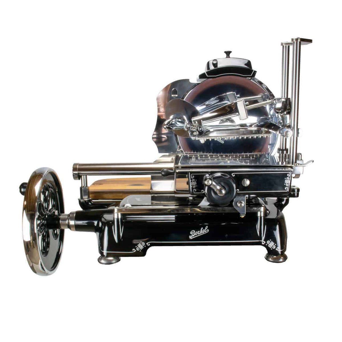 Der Berkel Volano Tribute Allesschneider in Schwarz ist ein Vintage-Fleischschneider mit Handbetrieb, der über ein großes rundes Messer und ein Handkurbelrad verfügt. Dieses Modell besticht durch dekorative Akzente und ein kunstvolles, poliertes Retro-Erscheinungsbild mit Blumenschwungrad-Design, komplett mit Ständer und Schneidebrett aus Fassholz.