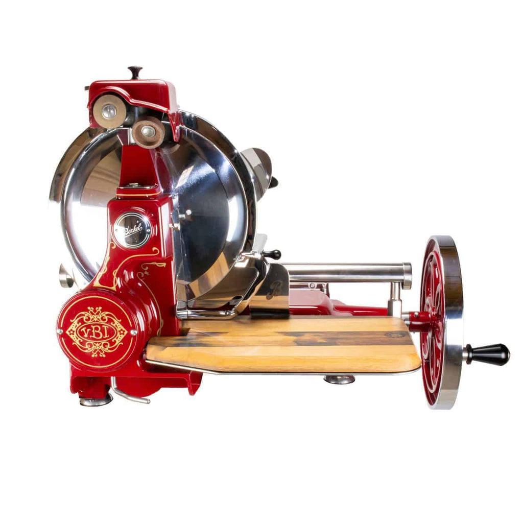 Die manuelle Aufschnittmaschine Berkel Volano B114 Rot mit passgenauem Einlegebrett, eine antike Fleischschneidemaschine in Rot und Silber, verfügt über ein großes rundes Messer, eine hölzerne Schneideplattform und ein Handkurbelrad an der Seite. Mit ihren kunstvollen Details und ihrem traditionellen Design besticht diese Maschine durch ein Vintage-Aussehen.