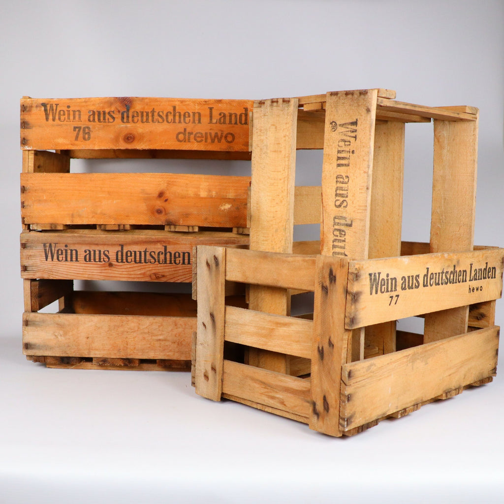 Drei Alte Weinkisten Holz Vintage aus der Pfalz in verschiedenen Größen sind gestapelt und nebeneinander aufgestellt. Auf jeder Kiste ist seitlich der deutsche Text „Wein aus deutschen Landen“ aufgedruckt. Die Kisten sind verwittert und zeigen ihren Vintage-Charme.
