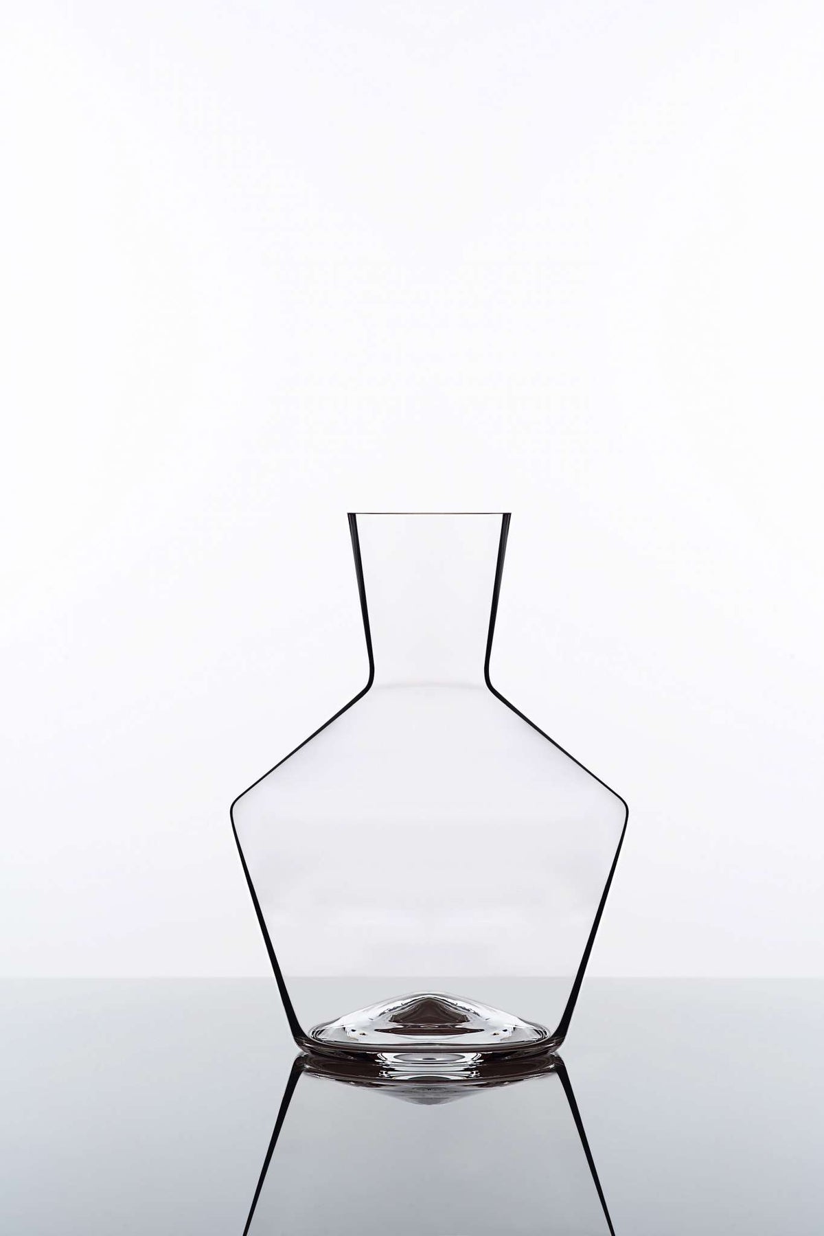 Eine elegante, moderne Glasvase mit eckigen Designelementen, die einen breiten Boden aufweist, der sich nach innen zu einem schmalen Hals verjüngt. Die Vase ist leer und steht vor einem schlichten weißen Hintergrund, wobei ihre Spiegelung auf einer glänzenden Oberfläche darunter sichtbar ist.